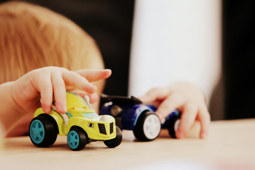 neném brincando com dois carrinhos em cima de uma mesa