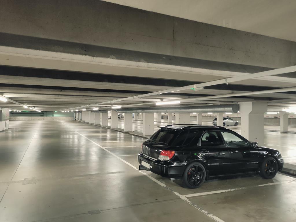 estacionamento coberto iluminado com luzes artificiais com três carros estacionados nas vagas